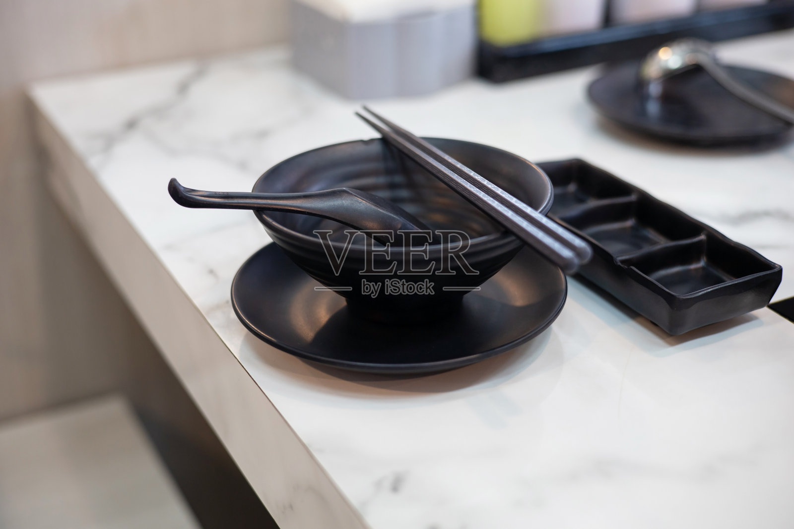 黑色的盘子和筷子放在餐馆的桌子上。照片摄影图片