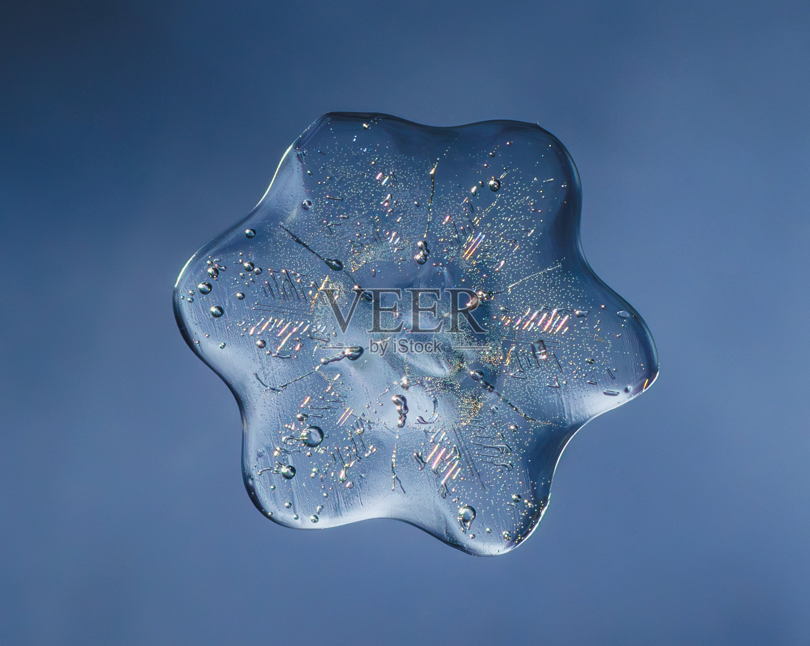 雪花在光滑的渐变背景。玻璃表面真实雪晶的微距照片。这是一朵花纹不寻常的小雪花。照片摄影图片