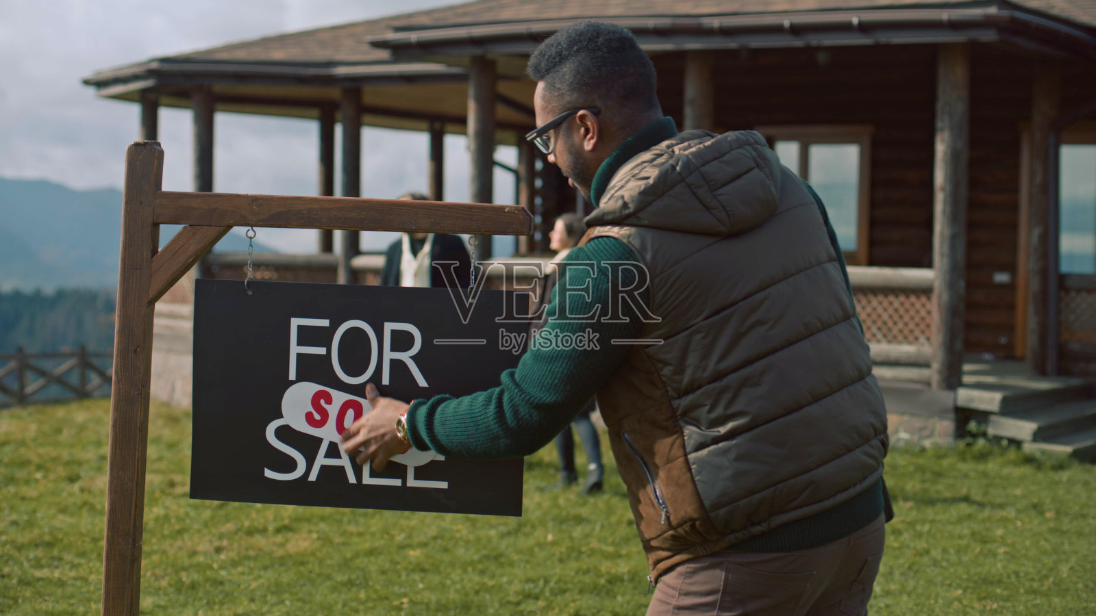 非裔美国房地产经纪人将出售标签贴在待售标牌上照片摄影图片