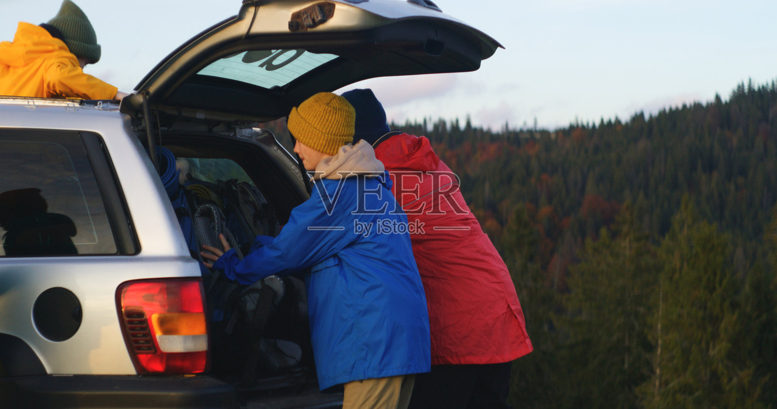 快乐的徒步伙伴从车里走出来，聊天，背上背包照片摄影图片