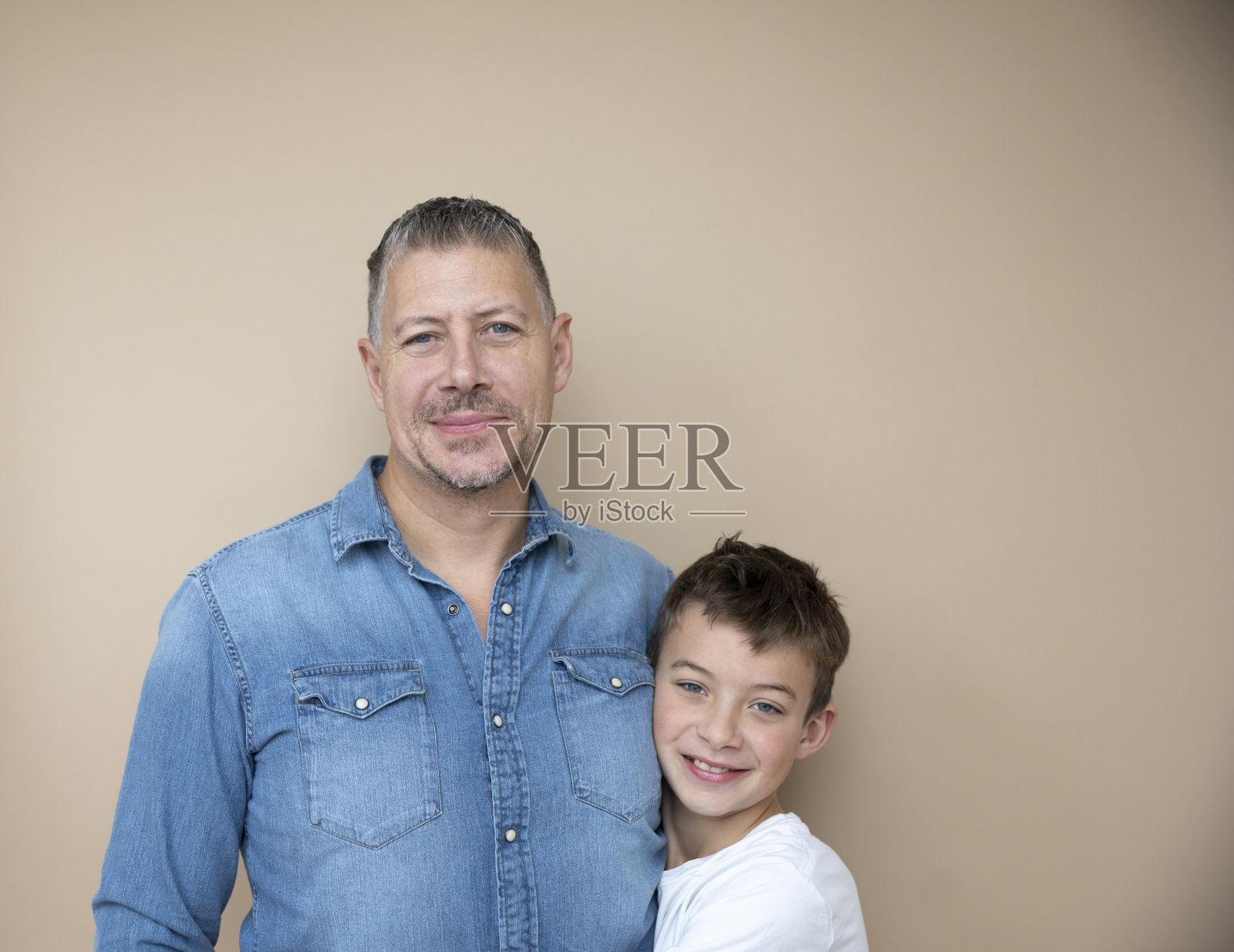 父亲和儿子在棕色背景前摆姿势，爱，家庭，青少年照片摄影图片