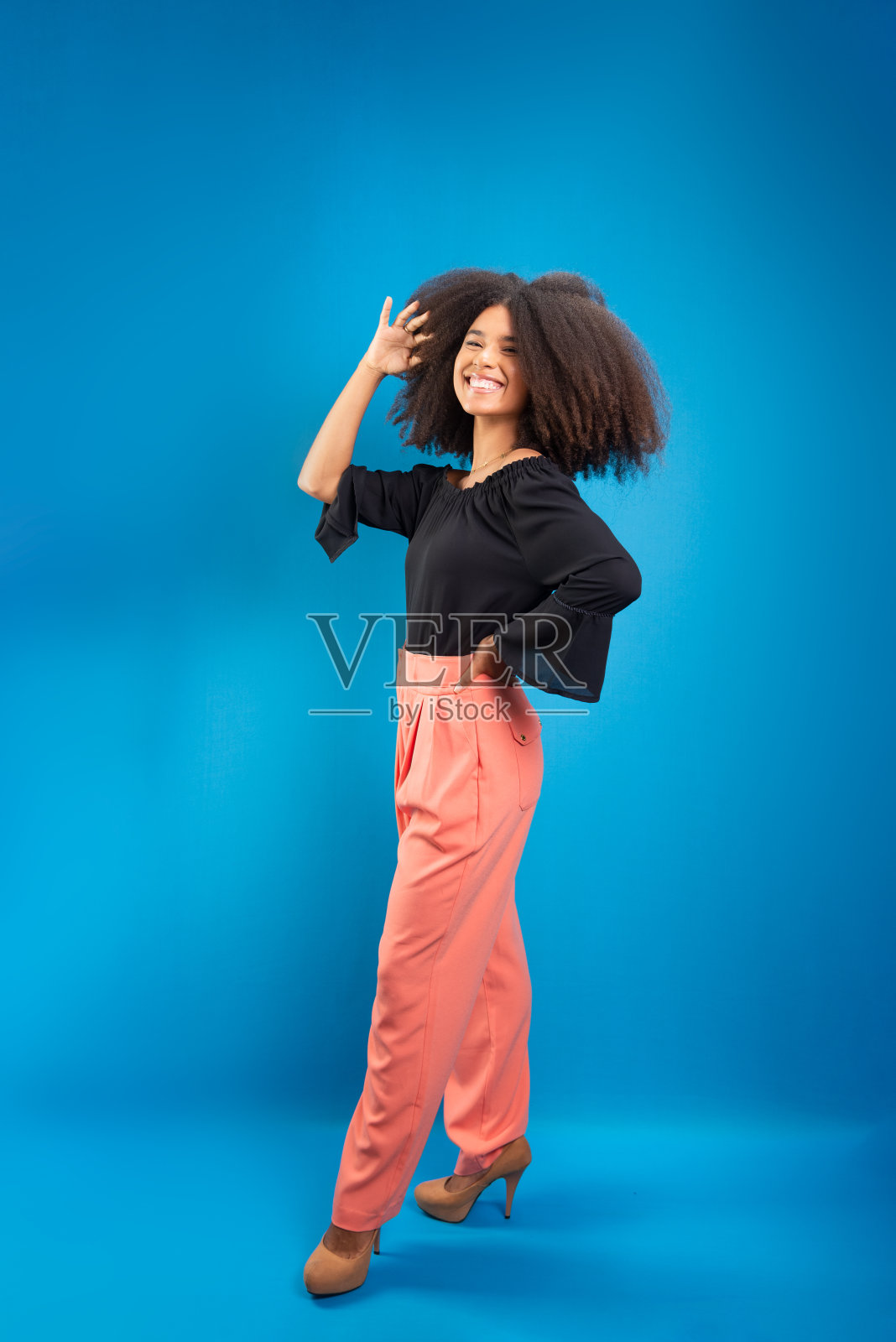 漂亮的年轻女子，站着，穿着便服，抚摸着她乌黑的长发。照片摄影图片