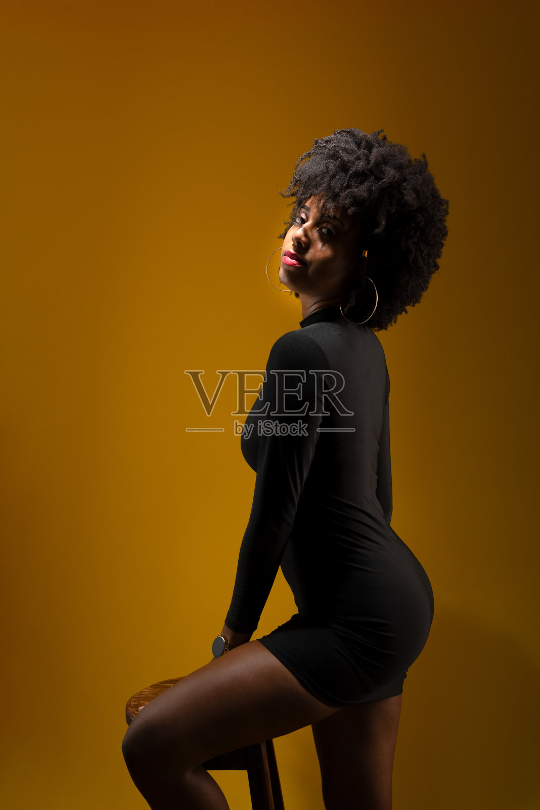 一个年轻女子的肖像，有着黑色的头发，穿着黑色的衣服，在昏暗的光线下摆姿势拍照。照片摄影图片