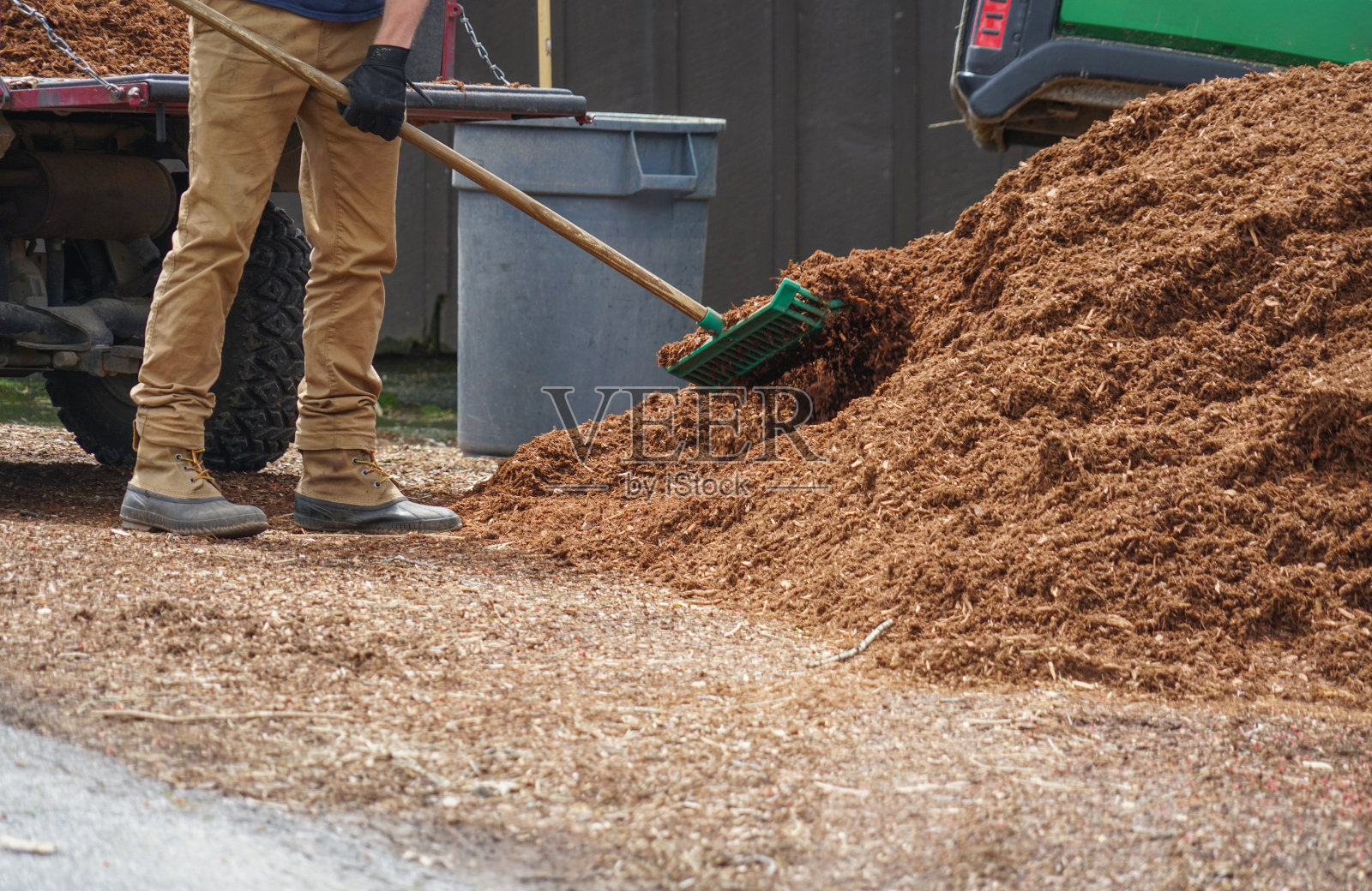 近距离拍摄正在为花园添加护根物的户外工人照片摄影图片