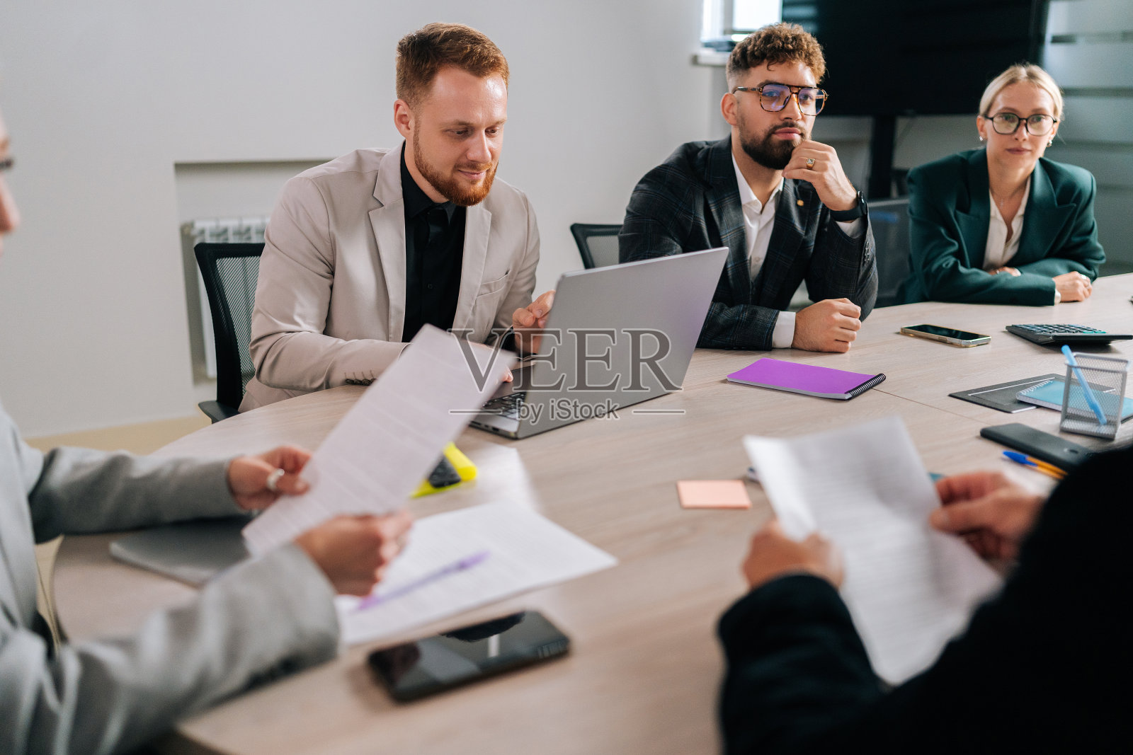 公司会议期间，年轻的商业团队就项目进行头脑风暴的广角镜头。男女员工分组倾听同事分享想法照片摄影图片