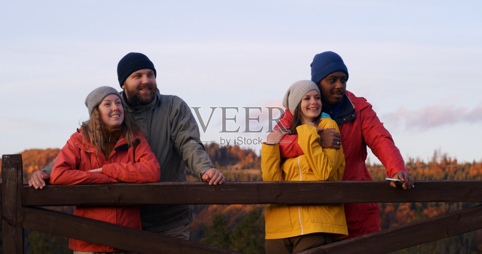 多民族夫妇站在木篱笆旁，看美丽的日落照片摄影图片