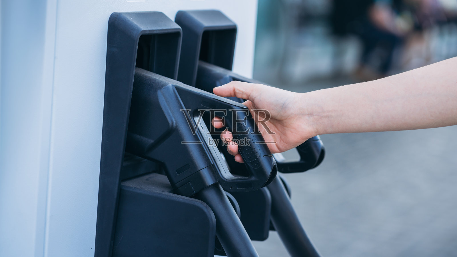 近距离电动车充电站。生态清洁能源理念。正在给电动车充电的妇女的手。方便的电动汽车充电器在手。照片摄影图片