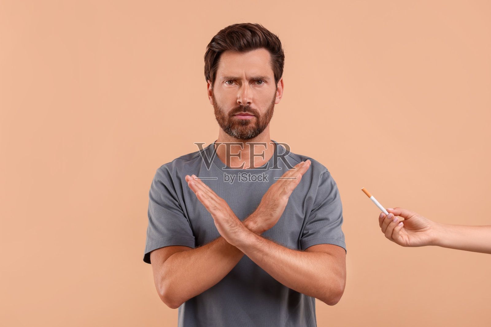 戒烟概念。浅棕色背景下拒绝吸烟的男子照片摄影图片