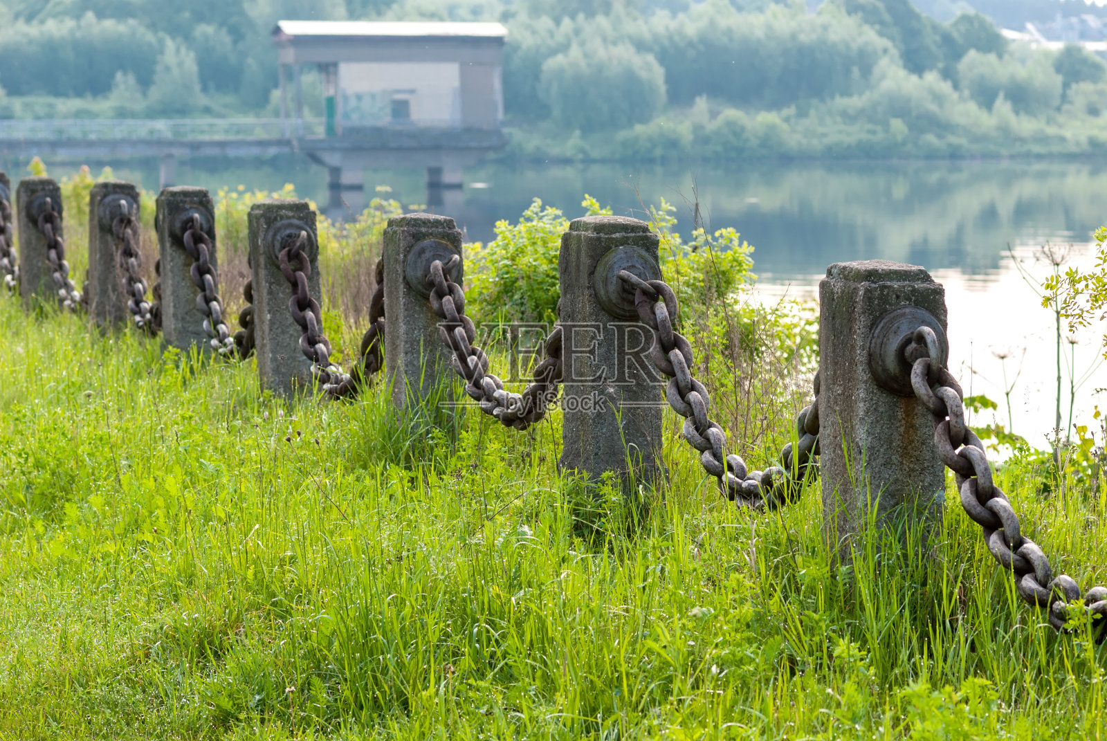 水结构的装饰性屏障，以钢链和花岗岩柱的形式。春天的风景。清晨的湖上。照片摄影图片