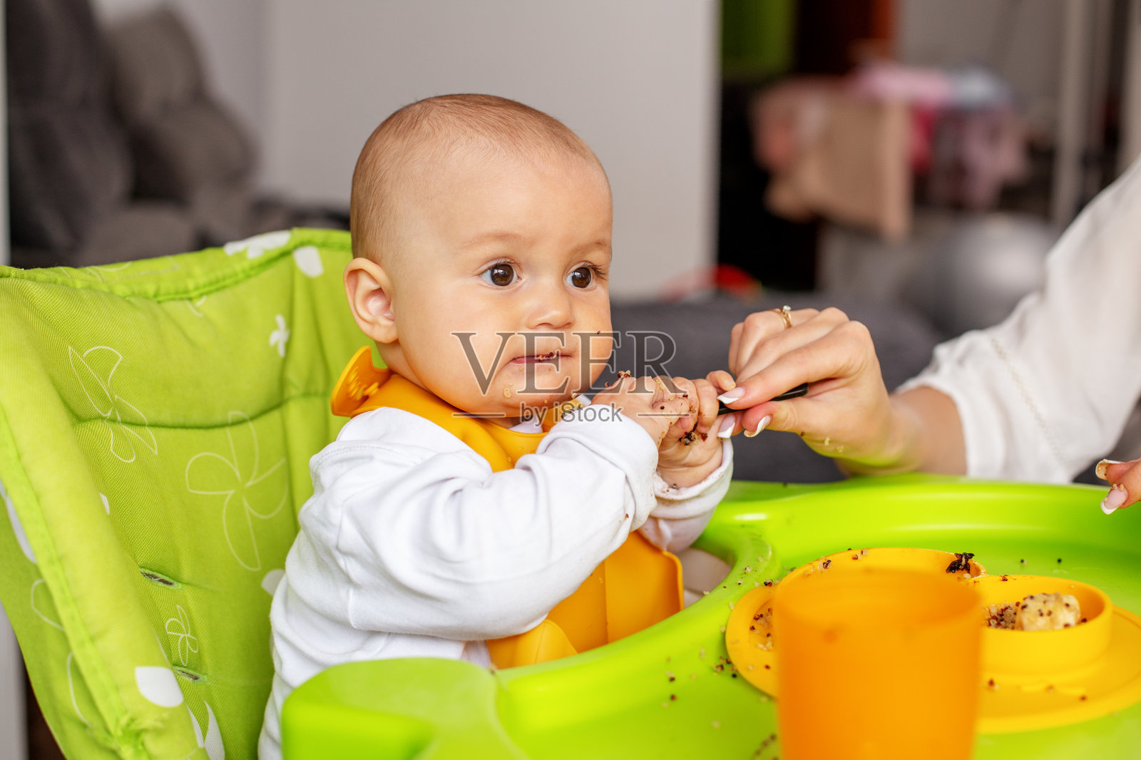 女婴坐在高脚椅上吃藜麦粥。喂养的概念。照片摄影图片