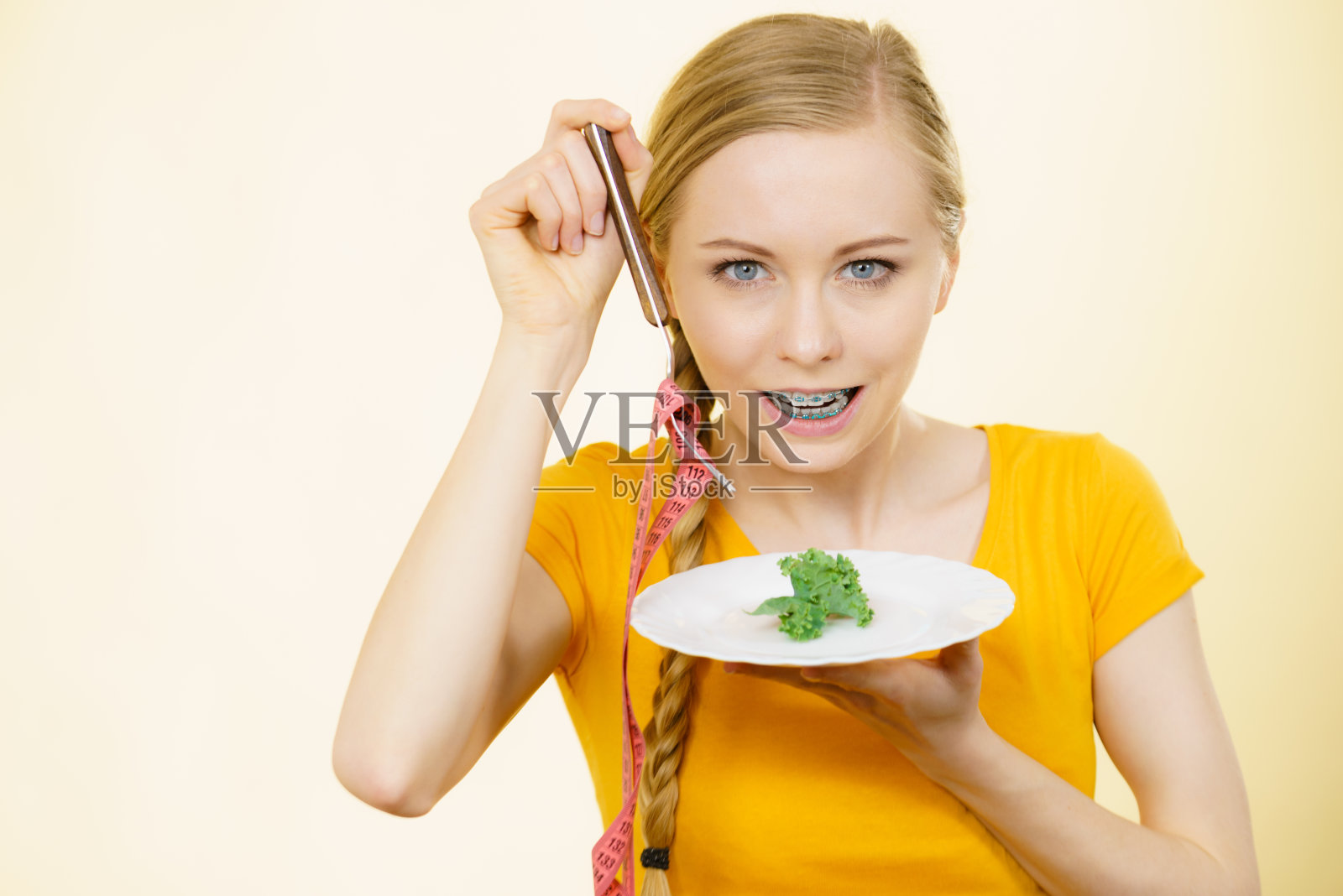 正在节食的女人端着盛有生菜的盘子照片摄影图片
