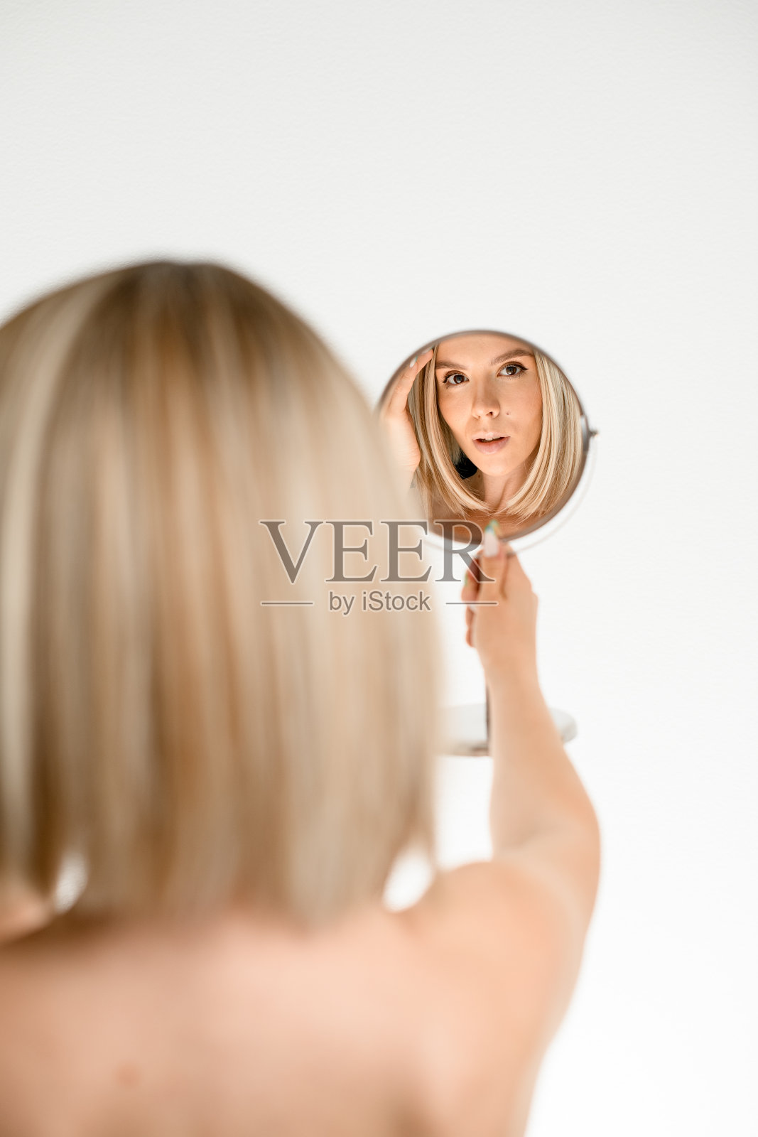 漂亮的金发女人，优雅的发型看着镜子照片摄影图片