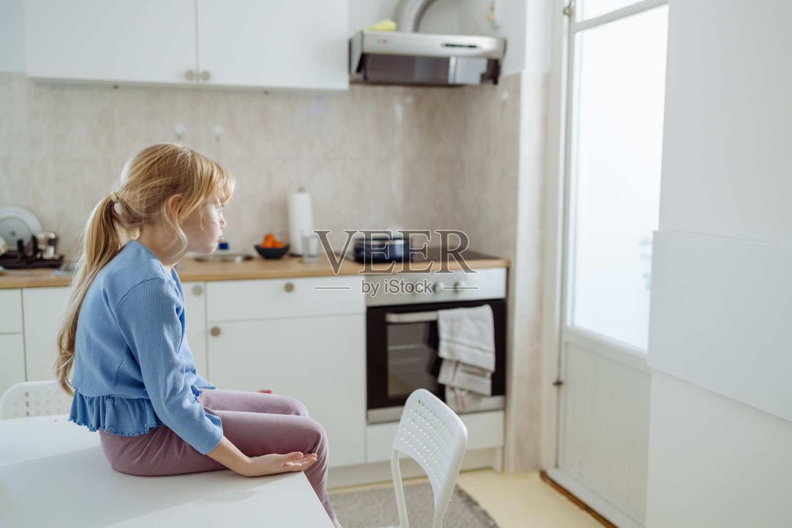 悲伤的小女孩坐在桌旁照片摄影图片
