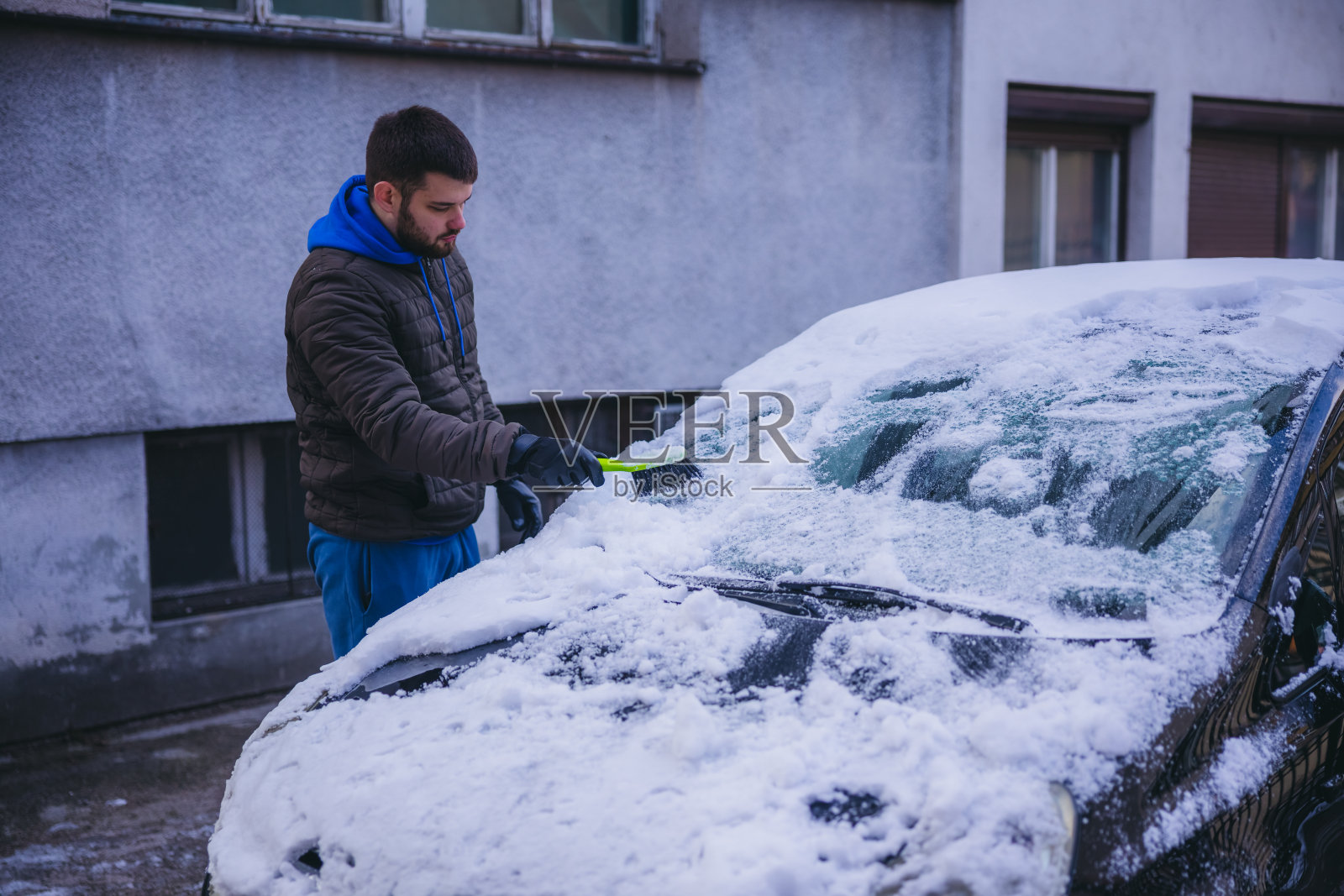 年轻人正在清除汽车上的积雪照片摄影图片