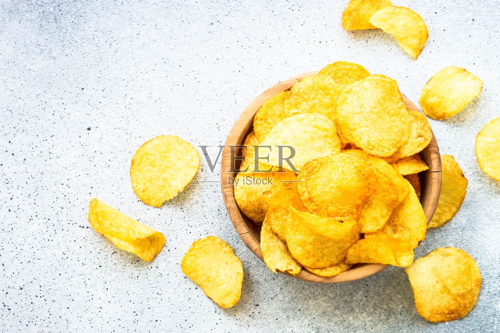 白色桌子上的木碗里装着薯片。前视图。照片摄影图片