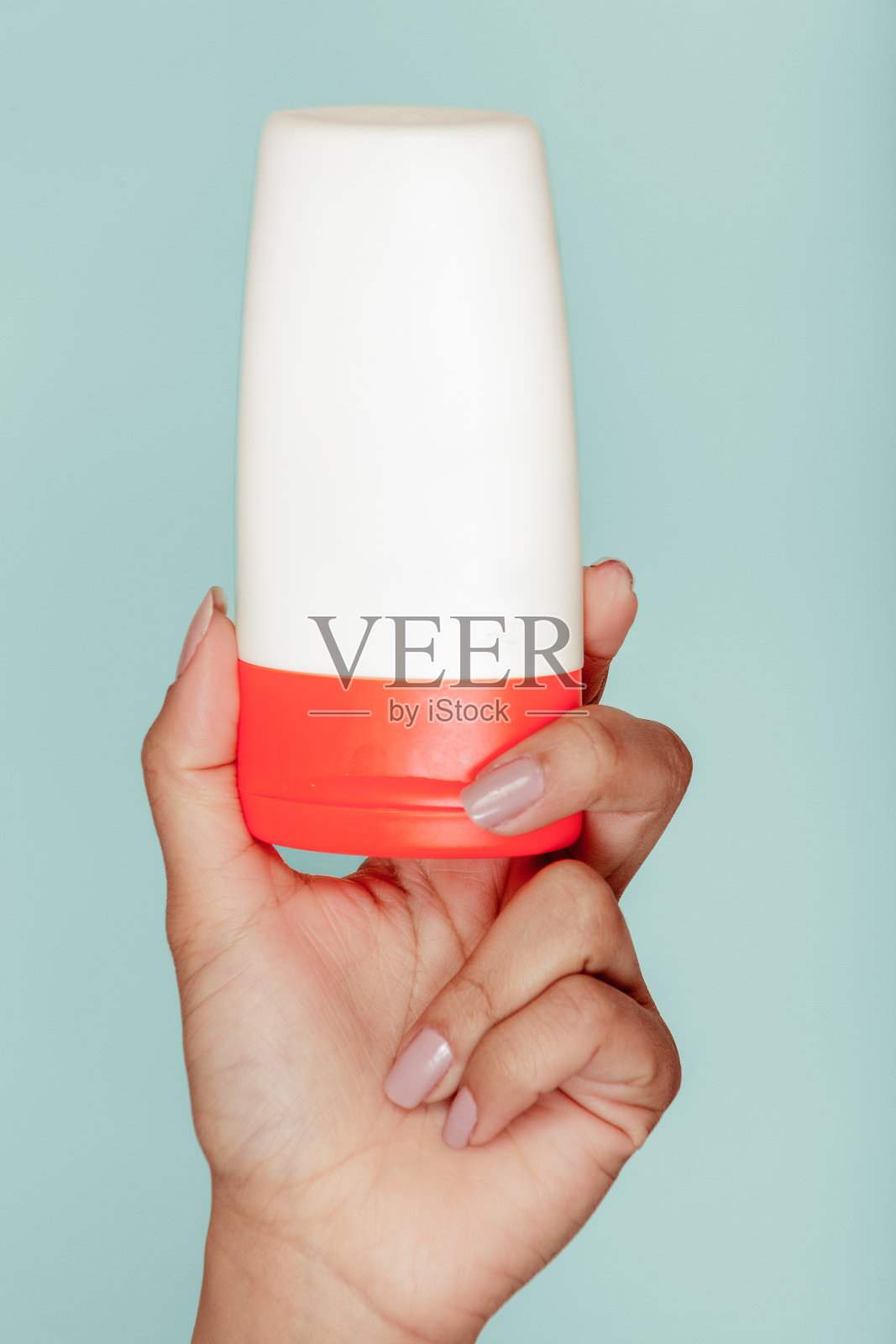 一个女人的手拿着一个蓝色背景的白色瓶子照片摄影图片