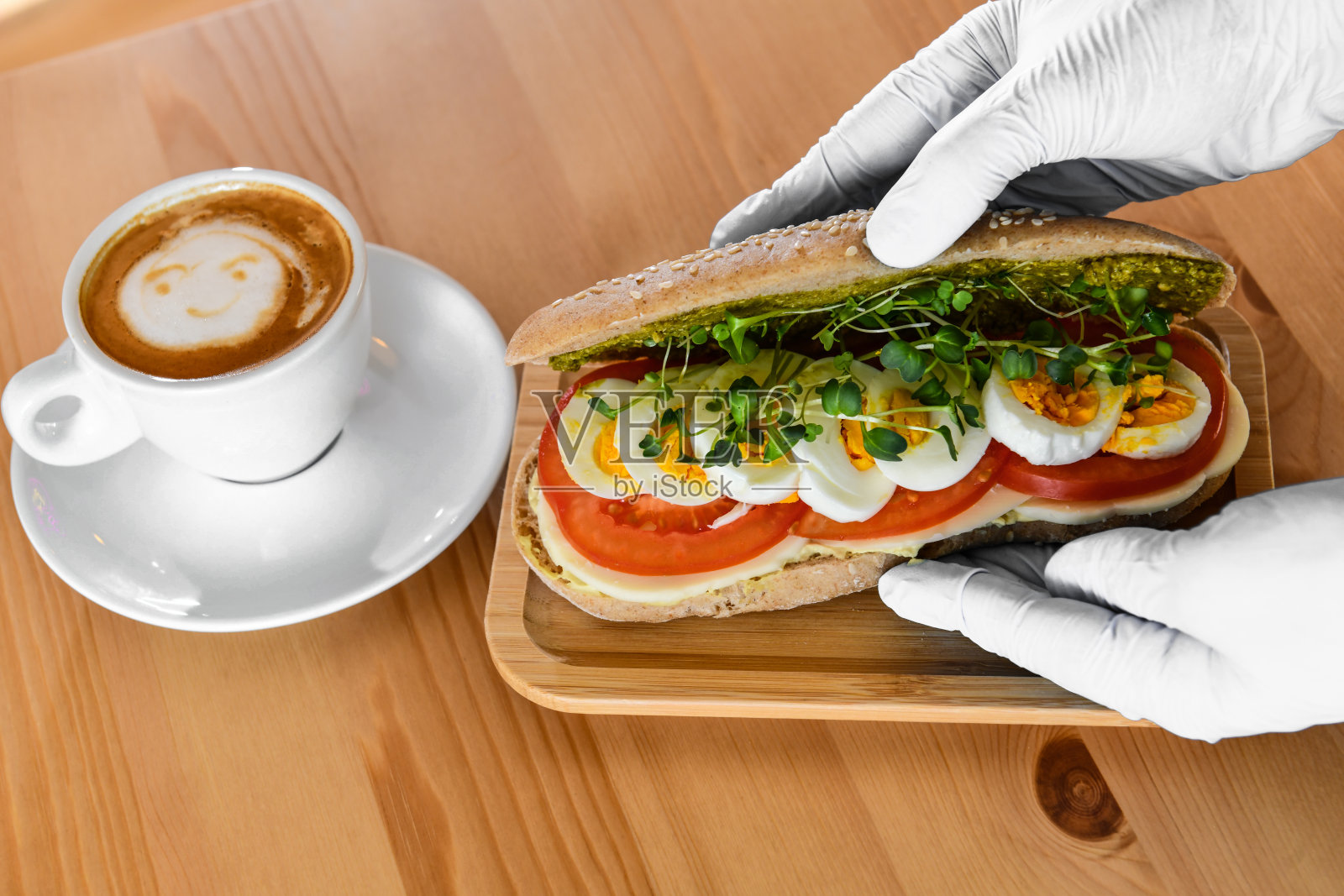 厨师把鸡蛋三明治放在木制盘子里，旁边是带笑脸的咖啡照片摄影图片