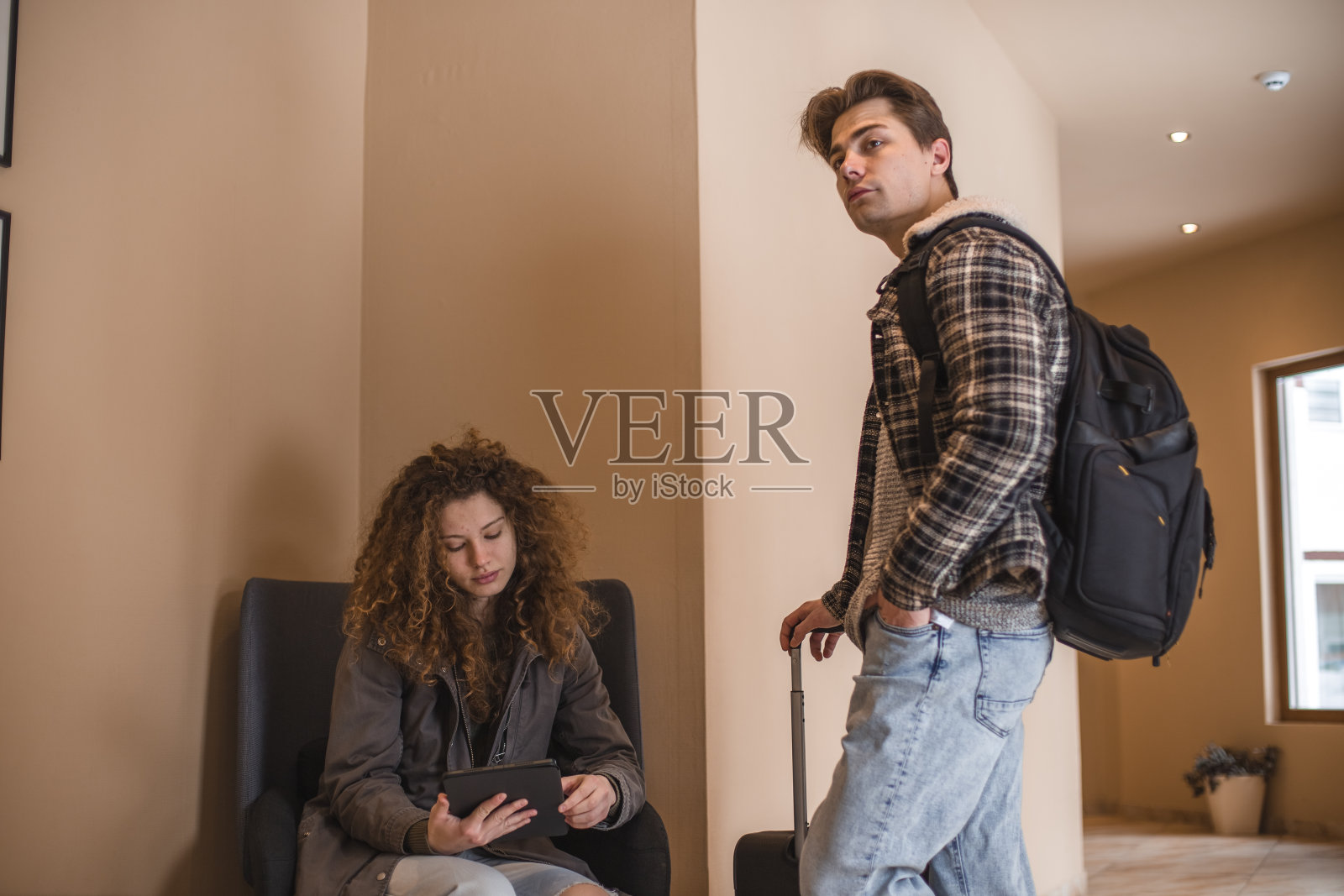 一对年轻的夫妇到达酒店，在走廊里等着，他们正在使用数码平板电脑照片摄影图片