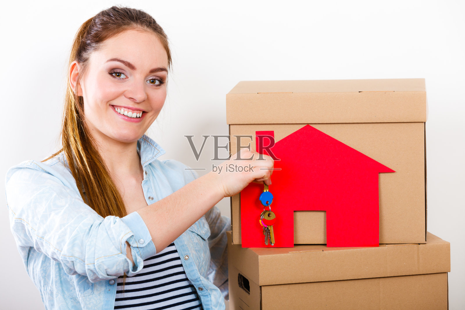 搬进来的女人拿着盒子和纸钥匙。照片摄影图片