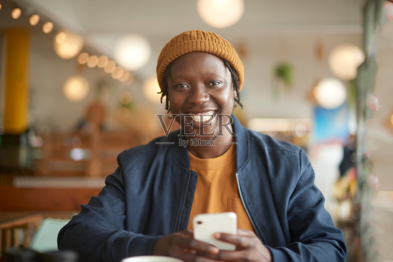 手机，快乐和黑人在咖啡馆的画像在社交媒体，移动应用程序或互联网上。科技，微笑和年轻的非洲男性在咖啡店用手机打短信。照片摄影图片