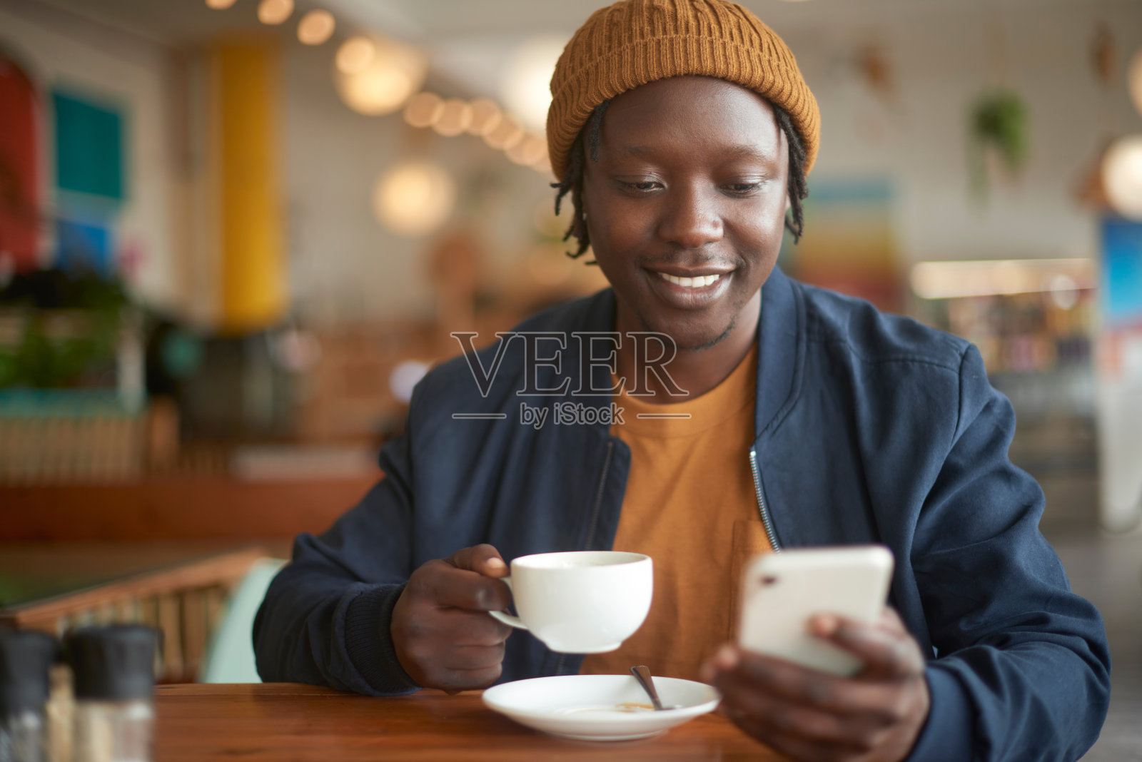 手机、咖啡和年轻黑人在社交媒体、移动应用程序或互联网上的交流。科技，研究和非洲男性在咖啡馆喝着卡布奇诺，用手机打短信。照片摄影图片