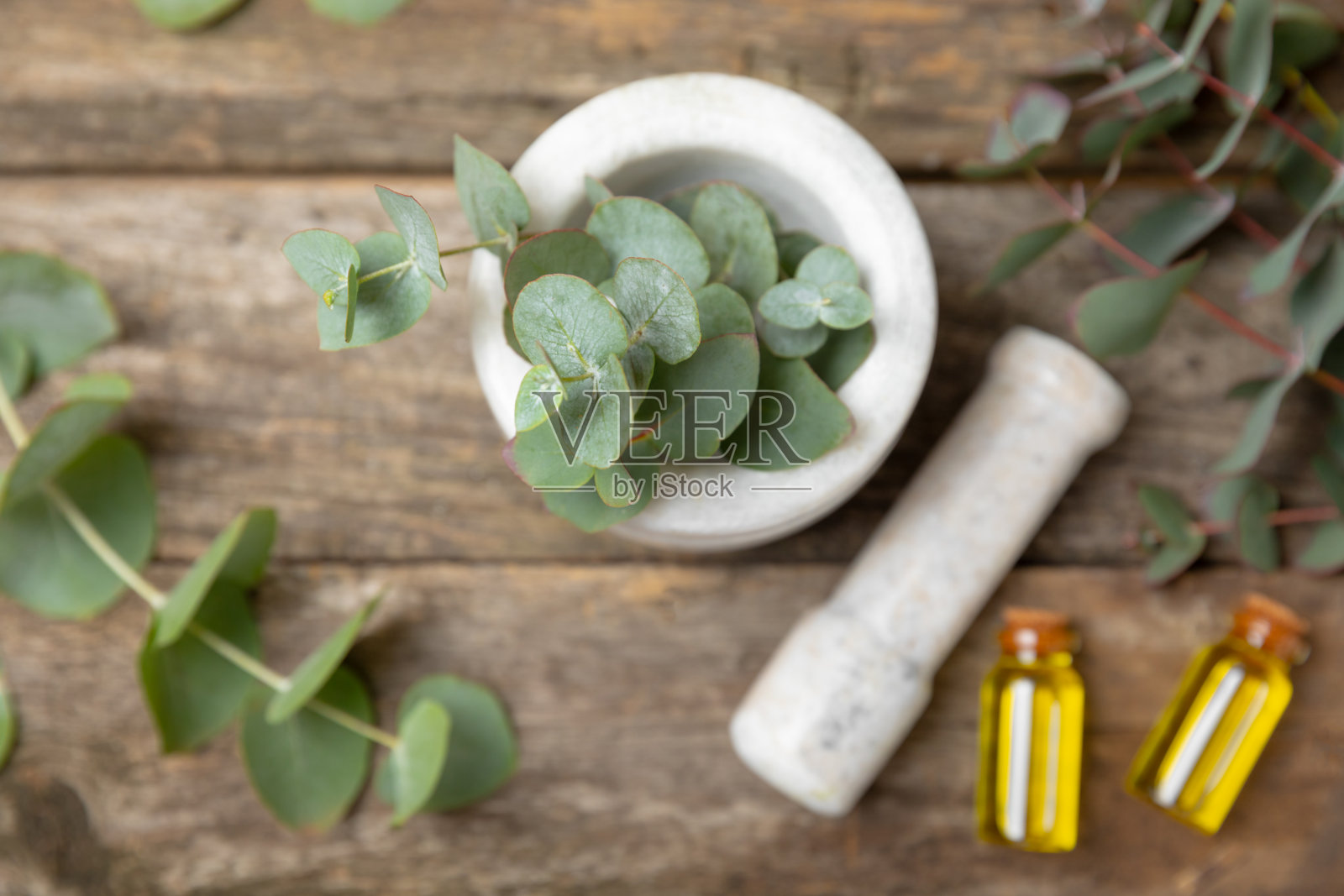 木质背景上的桉树叶和灰浆。水疗中心的概念。替代药物和天然化妆品成分。一瓶精油和一些桉树。有机护肤照片摄影图片