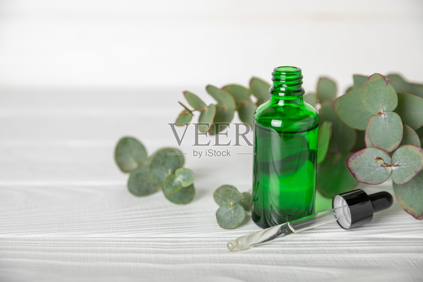 桉树精油在一个玻璃瓶子与绿色桉树叶子纹理木制背景。芳香疗法的概念。水疗中心。天然有机成分，用于化妆品和身体护理。本空间照片摄影图片