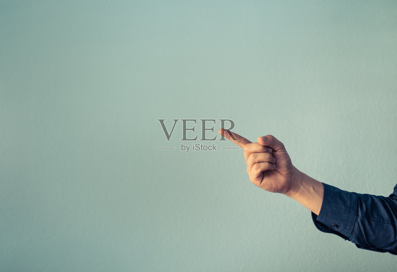 用手指指着有复印空间的绿色墙壁。照片摄影图片