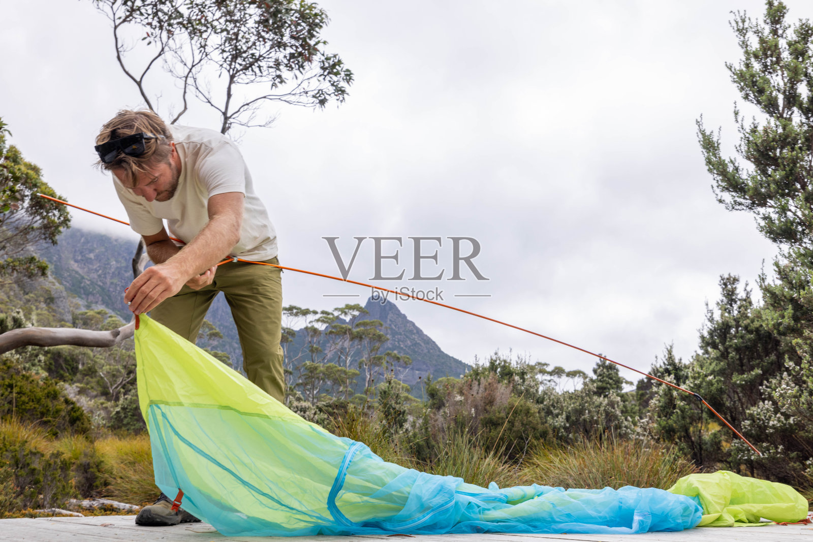 荒野静修:在塔斯马尼亚宁静的风景中，一名男子在木平台上搭帐篷照片摄影图片