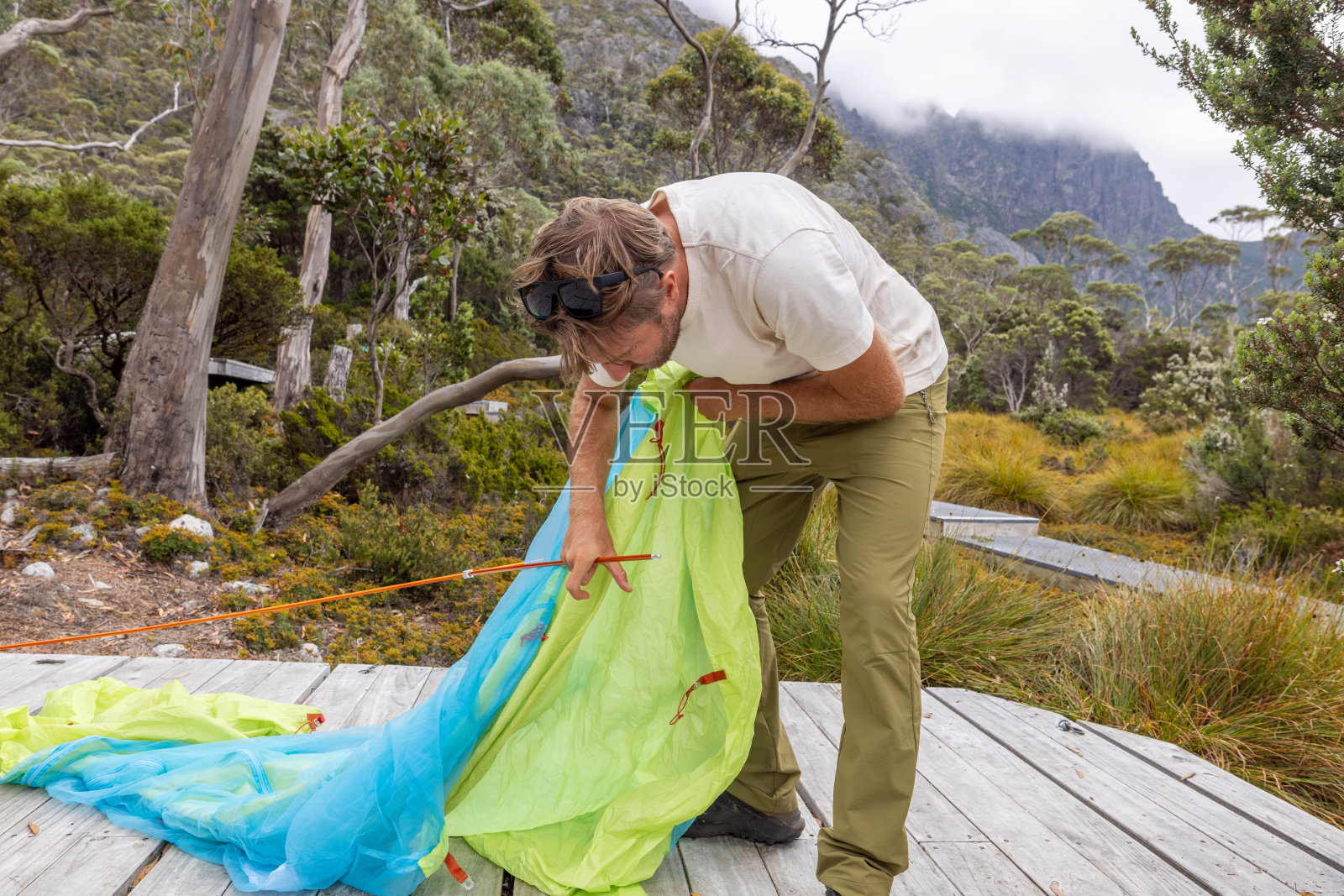 荒野静修:在塔斯马尼亚宁静的风景中，一名男子在木平台上搭帐篷照片摄影图片