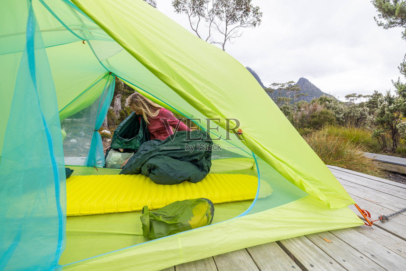 一位妇女在塔斯马尼亚长途跋涉后，在木平台上准备帐篷照片摄影图片