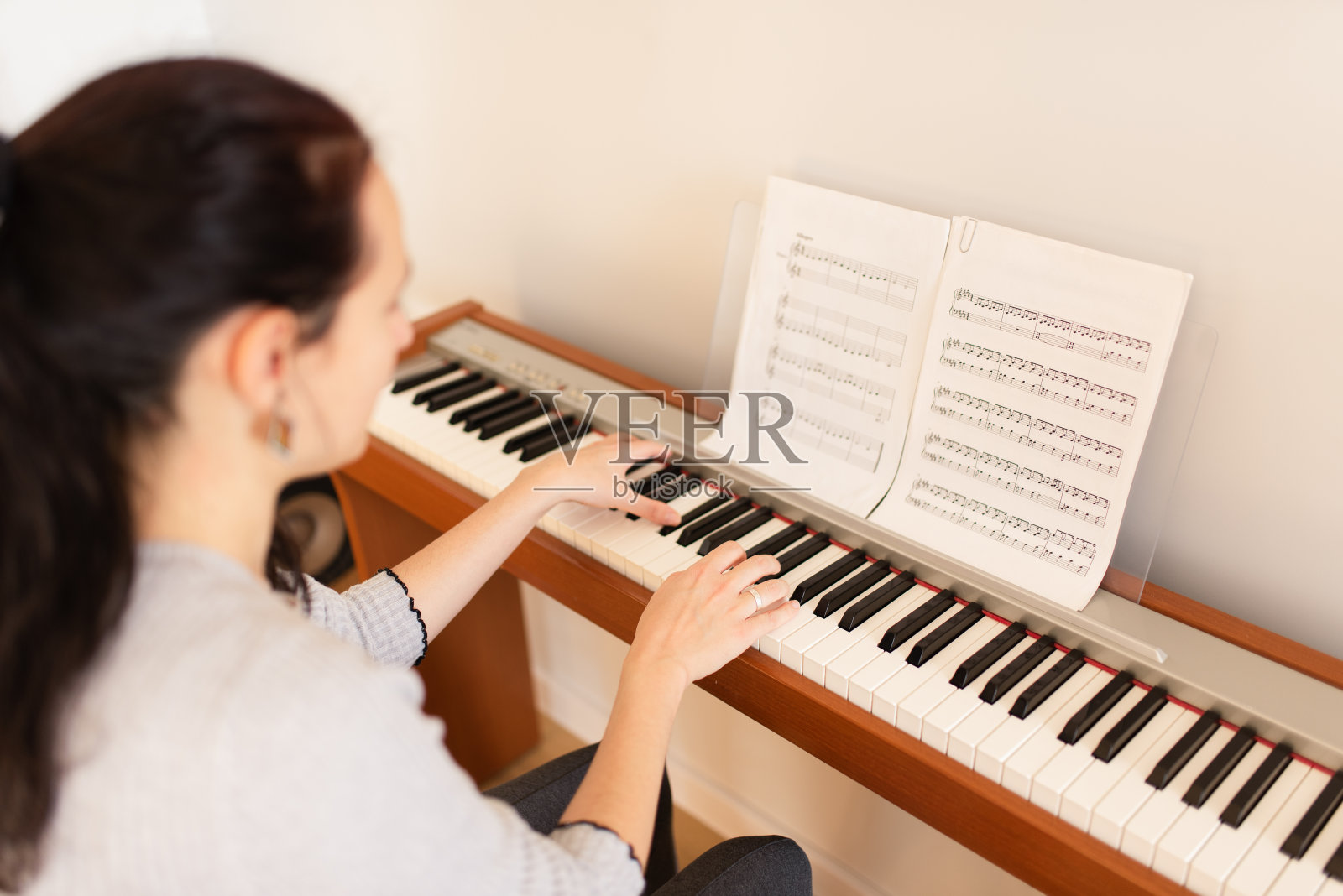 年轻的成年女子正在家里弹奏数码钢琴照片摄影图片