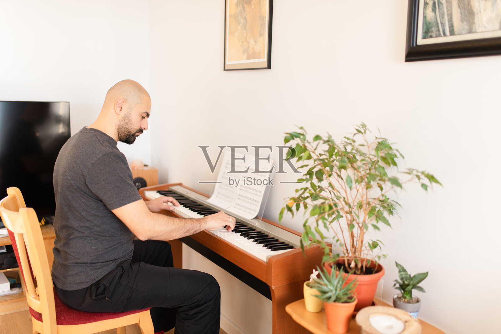 一个成年男子正在家里弹奏数码钢琴照片摄影图片