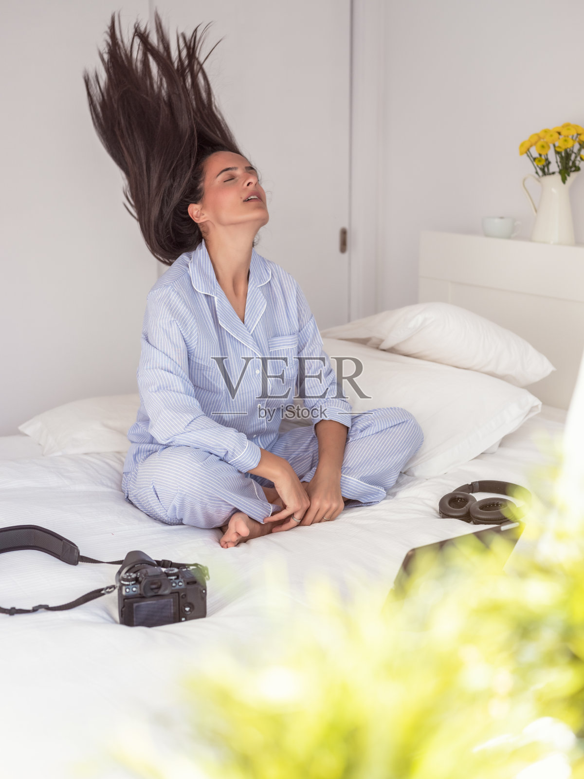 头发飞扬的女人拿着相机坐在床上照片摄影图片