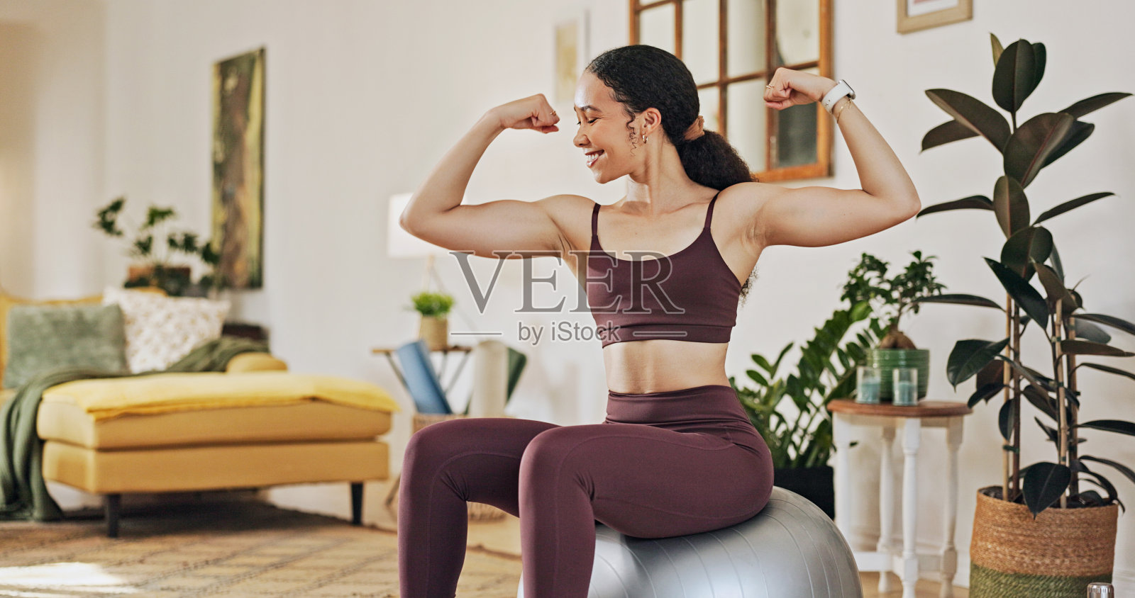 快乐的女人，坐在健身球上，在家里的客厅里健身、成长或锻炼。年轻女性的微笑与肌肉训练，普拉提或力量在健康和保健照片摄影图片