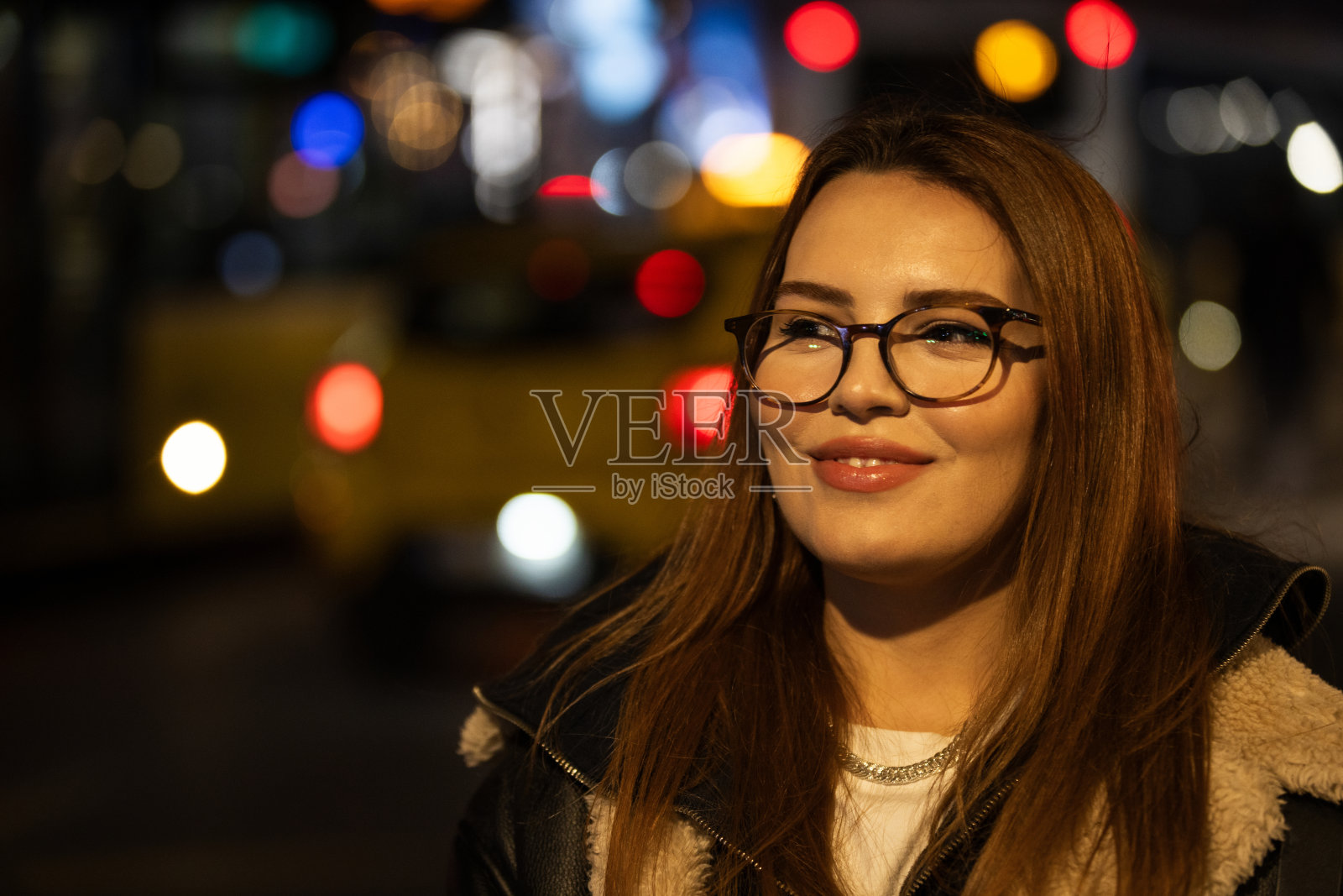 美丽的年轻女子在城市灯光前的肖像。照片摄影图片