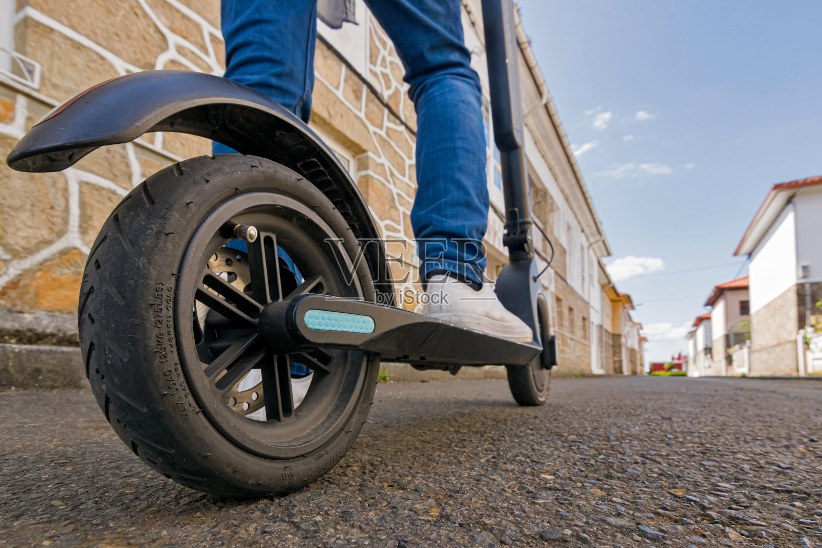 一个年轻人在电动滑板车上的腿和脚照片摄影图片