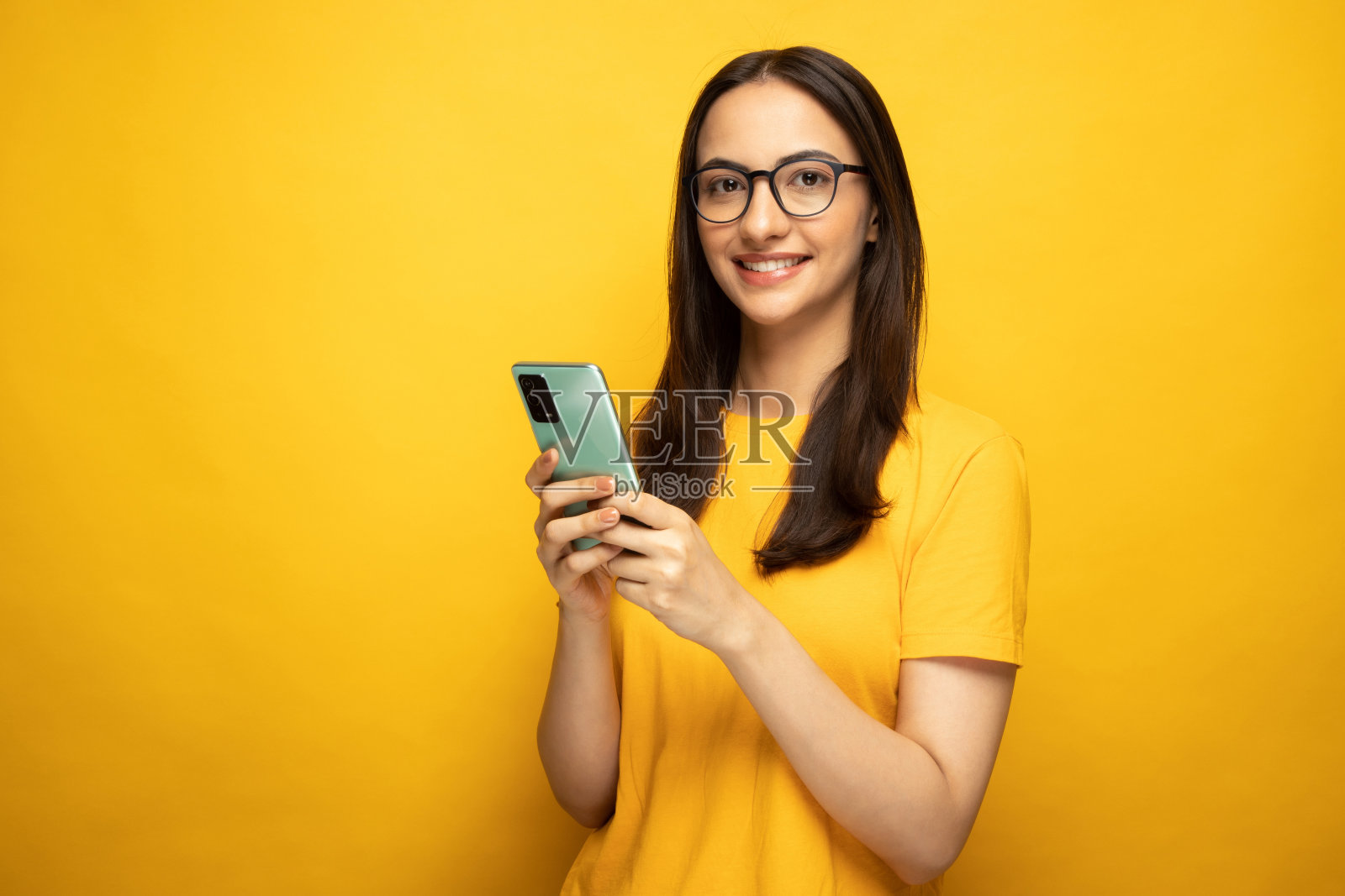 照片漂亮的年轻女孩使用手机黄色背景股票照片照片摄影图片