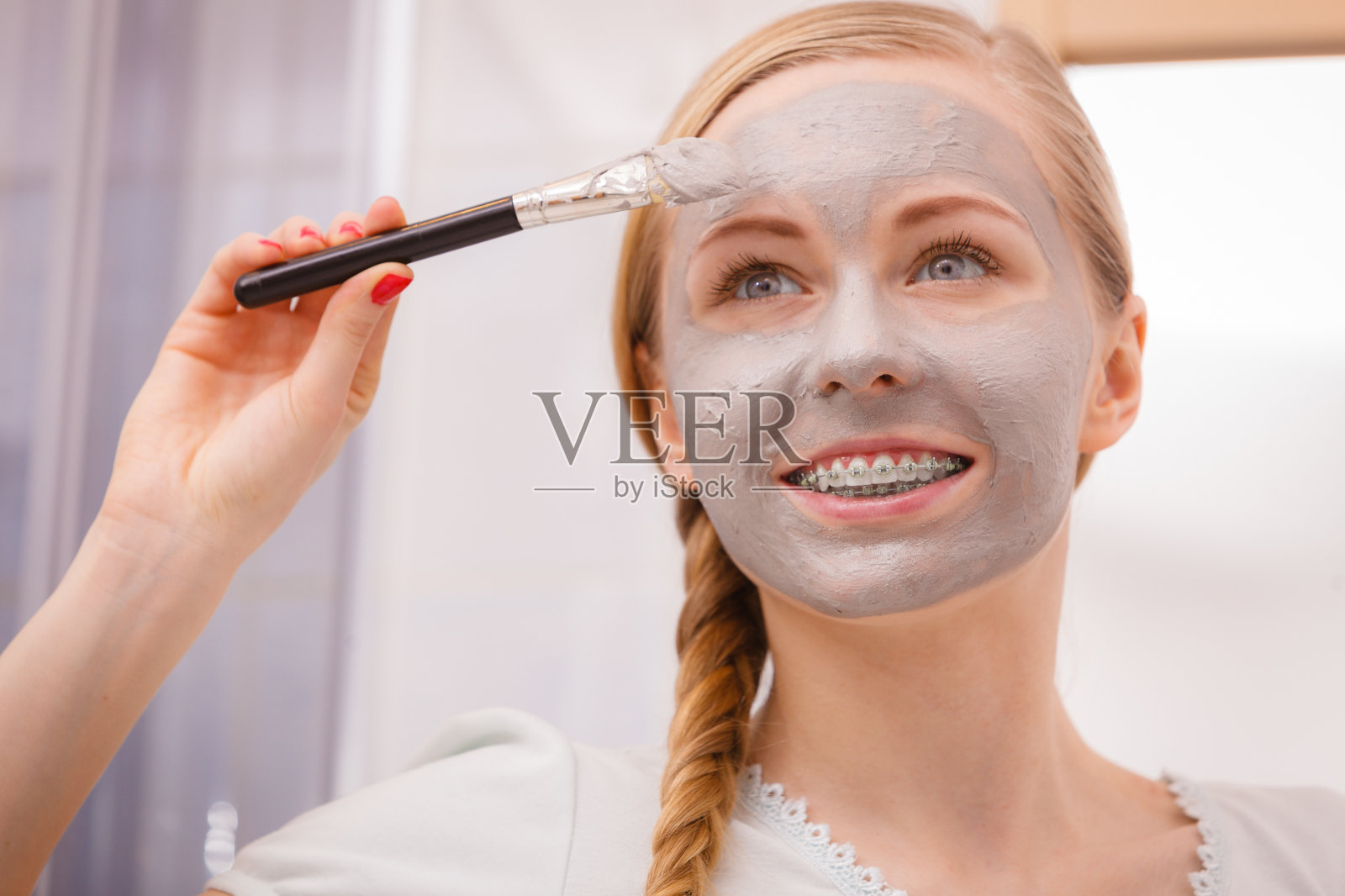 一名女子正在用刷粘土泥面膜敷脸照片摄影图片