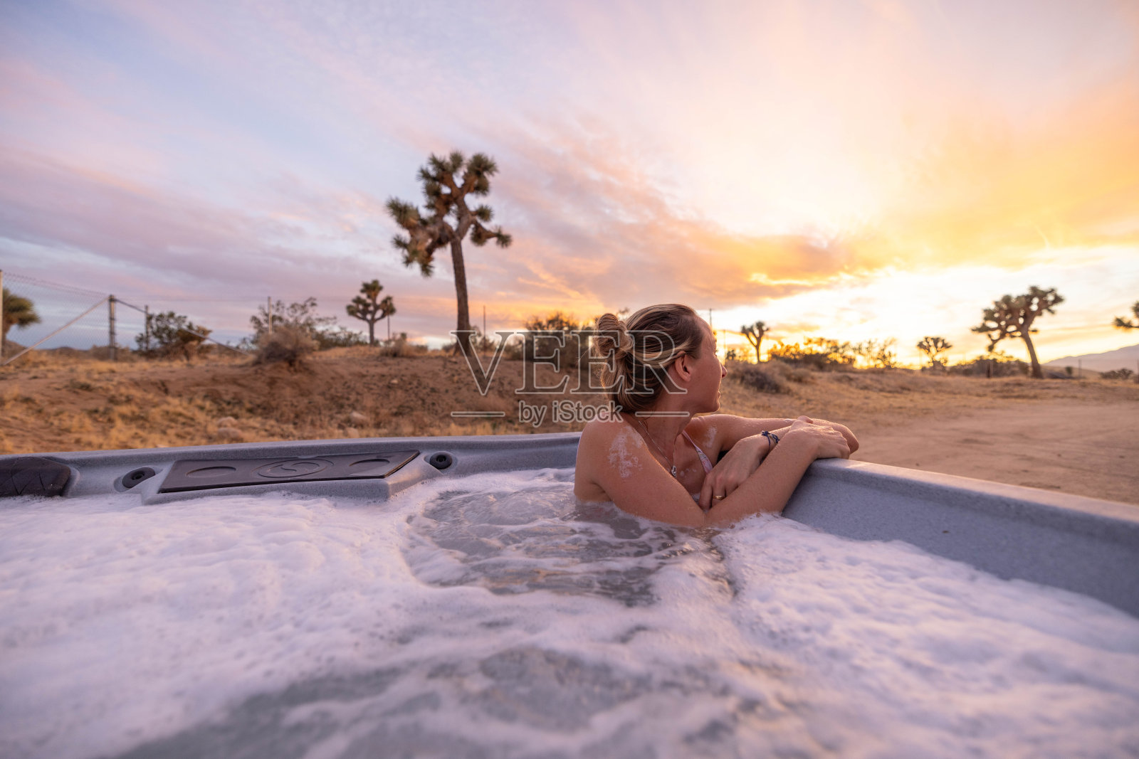 日落宁静:在沙漠日落下的自然戏剧中，女人在按摩浴缸中放松照片摄影图片