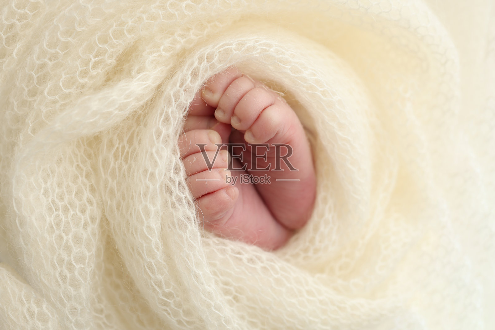新生婴儿的小脚。新生儿柔软的脚裹在白色的羊毛毯子里。新生儿的脚趾、脚跟和脚的近照。微距摄影。照片摄影图片