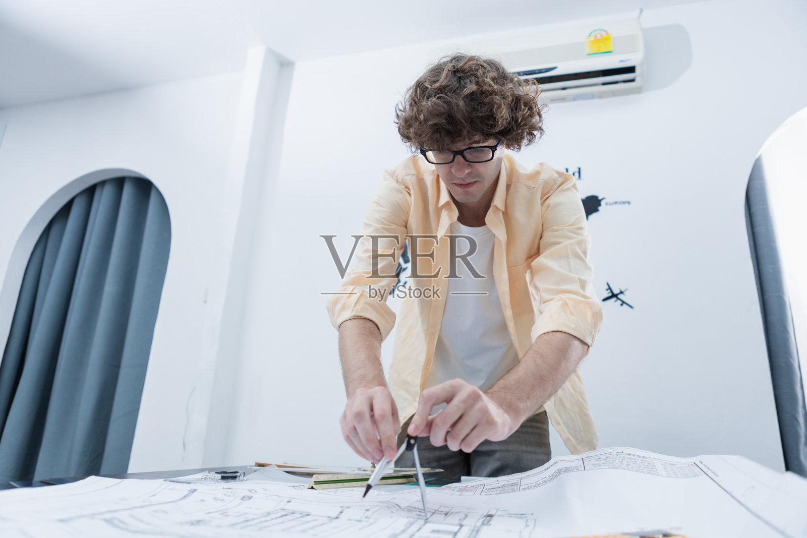 年轻的建筑师利用圆规绘制几何图形设计房屋方案。新的建筑和室内设计理念。男专业素描房屋建筑结构上的文书工作。照片摄影图片