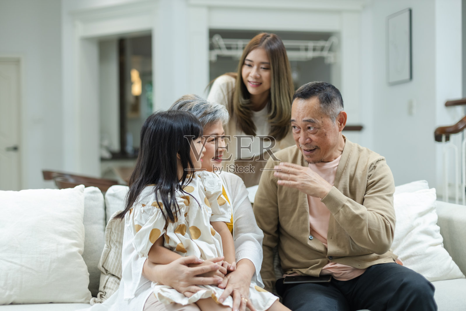快乐的家庭，爷爷，奶奶和孙女在家里的客厅里玩得很开心。连接不同年龄的关系。放松时间孩子与父母，家庭幸福理念。照片摄影图片