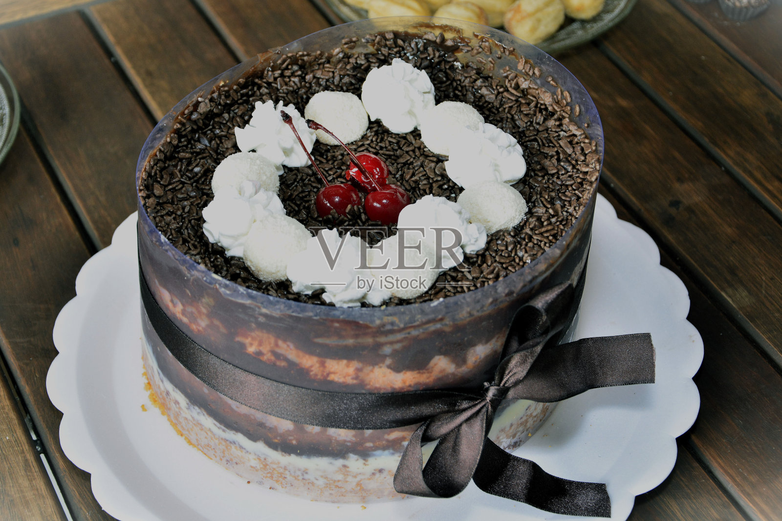 蛋糕装饰有巧克力屑，生奶油，焦糖乳清粉，红樱桃和漂亮的棕色缎带蝴蝶结照片摄影图片