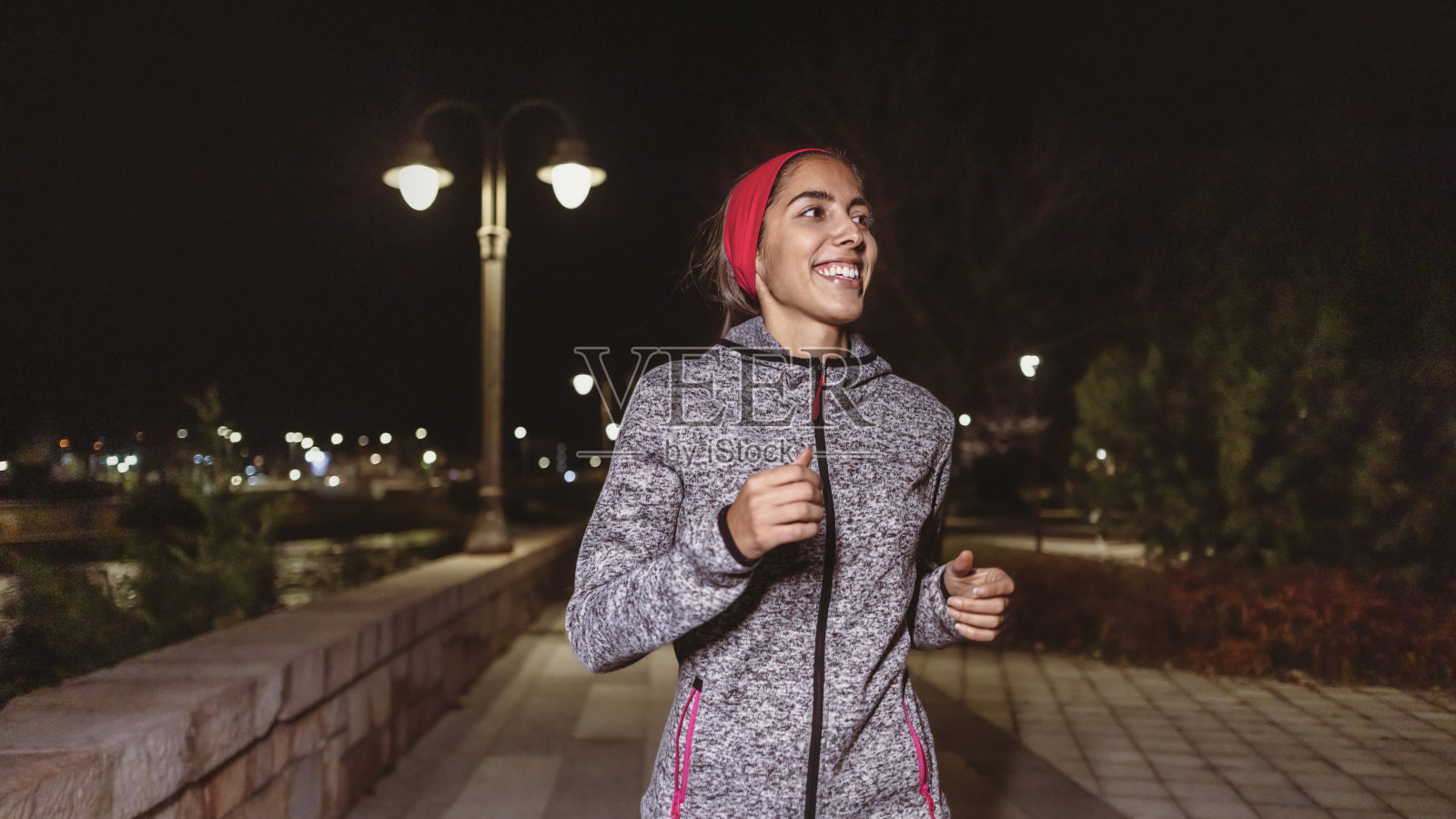 一位身着运动服的年轻西班牙女性的肖像，她在夜晚在码头边跑步照片摄影图片