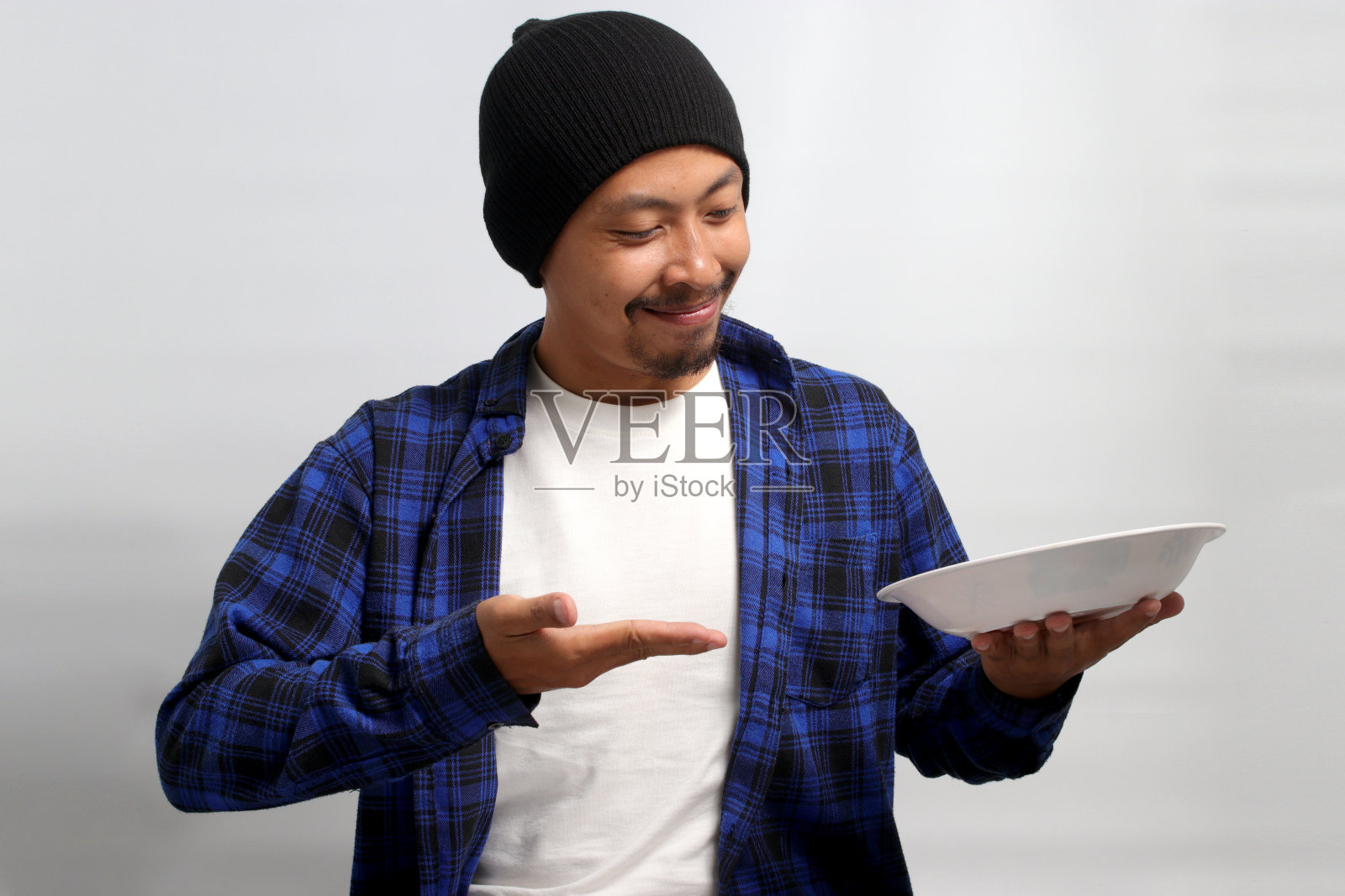 兴奋的年轻亚洲男子正在展示一个空的白色盘子在他的手掌照片摄影图片