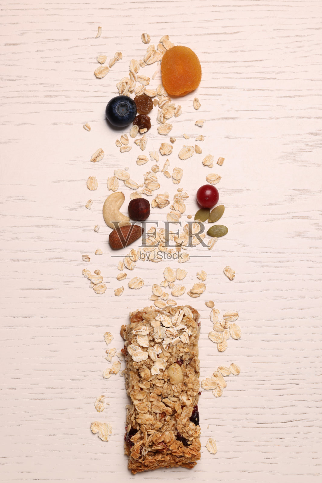 白色木桌上美味的格兰诺拉麦片棒和食材，俯视图照片摄影图片