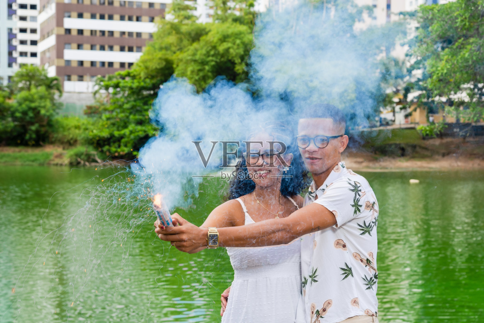 一对幸福的夫妇透过蓝烟发现他们的孩子是个男孩。性别。照片摄影图片