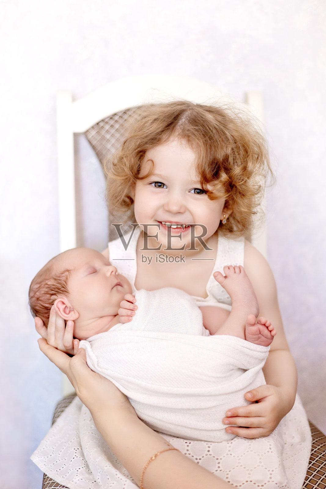 一个姐姐怀里抱着一个穿着白色尿布的新生女婴，这是一张特写照片照片摄影图片