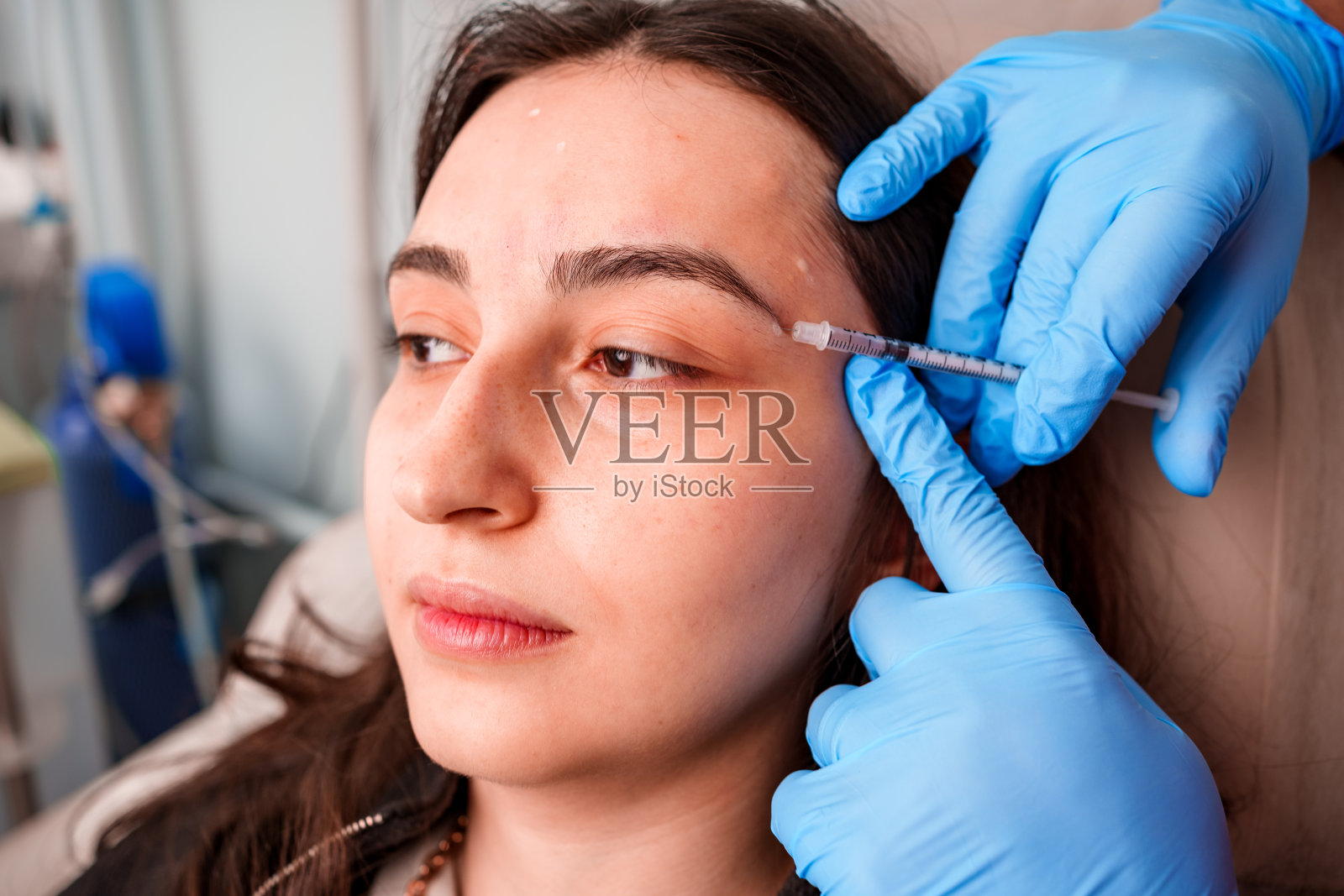 化妆师在年轻女性脸上注射肉毒杆菌的手特写照片摄影图片